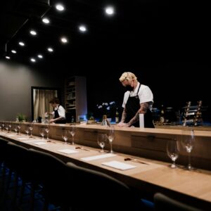Chefs preparing sushi at an elegant omakase bar in a dimly lit Japanese restaurant.