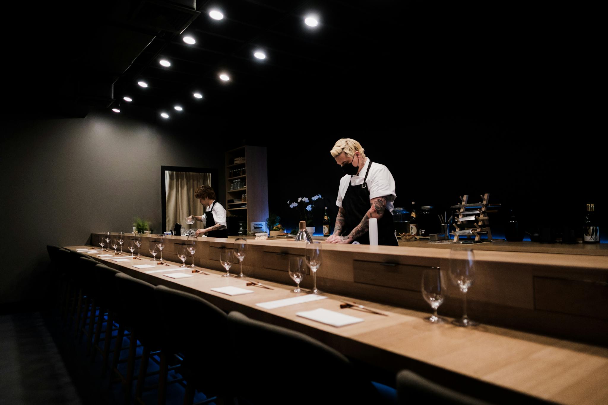 Chefs preparing sushi at an elegant omakase bar in a dimly lit Japanese restaurant.