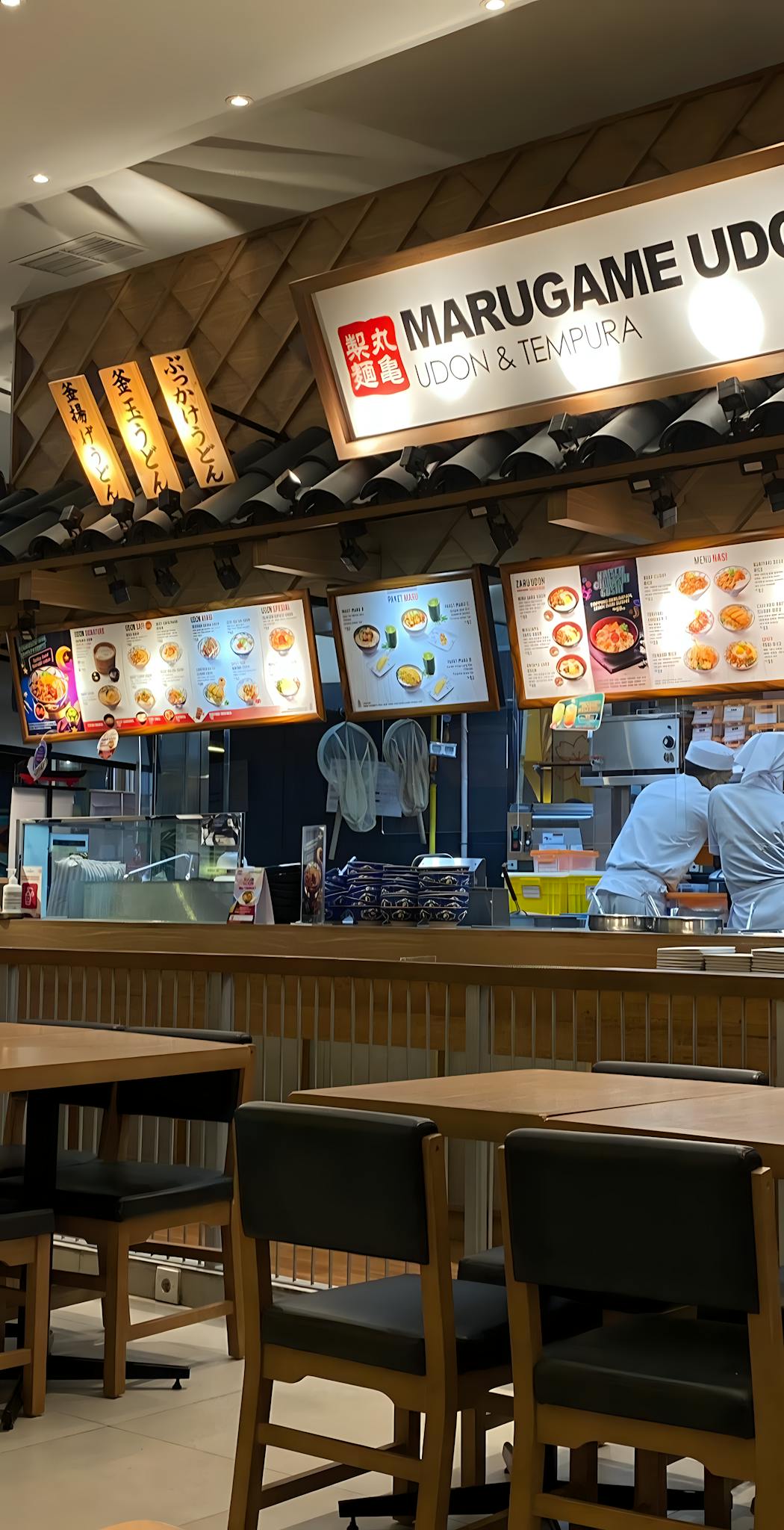 Cozy interior of Japanese restaurant with chefs preparing meals.