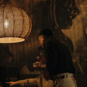 Dimly lit restaurant with waiter serving a table, emphasizing warm ambiance.